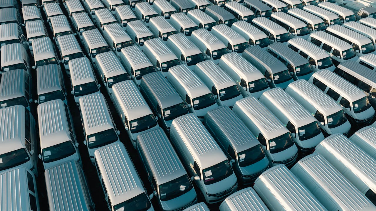creative-01 An aerial shot of a large fleet of white vans parked in rows under the early morning light in Libya.
